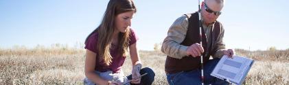 Two people surveying a large outdoor field