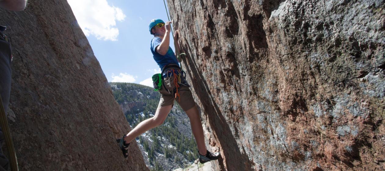 A student rock climbing on the side of a cliff