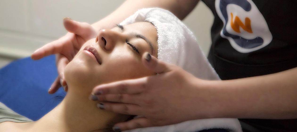 A cosmetology student practices giving a facial to a client. 