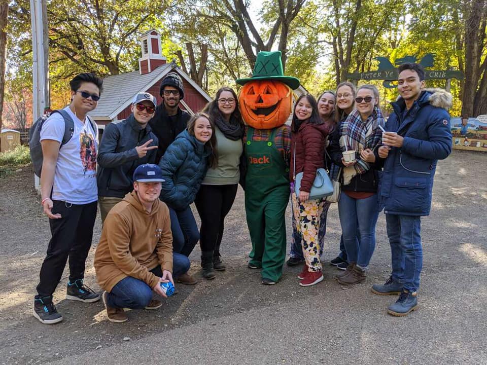 CWC students take a photo with a giant pumpkin at a pumpkin patch in Nebraska