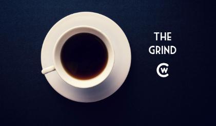 White coffee cup sits on a dark blue background with The Grind logo and CWC logo