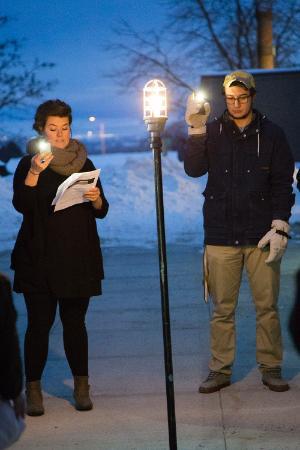 people gather around a light during the Ghostlight Project at dusk