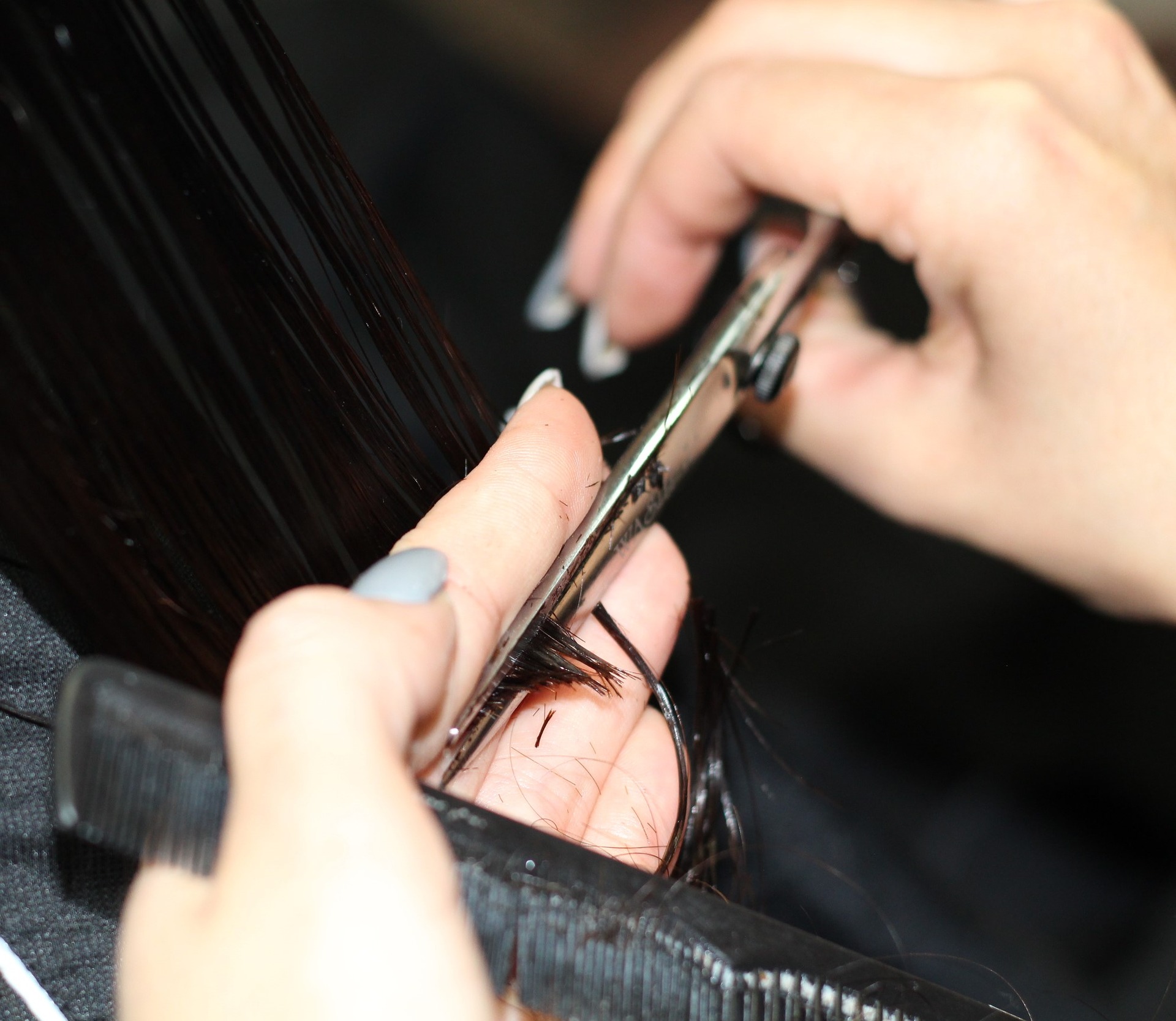 hairstylist holding scissors and a comb in their hands cutting hair