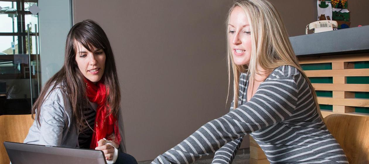 Two women discuss content on a computer