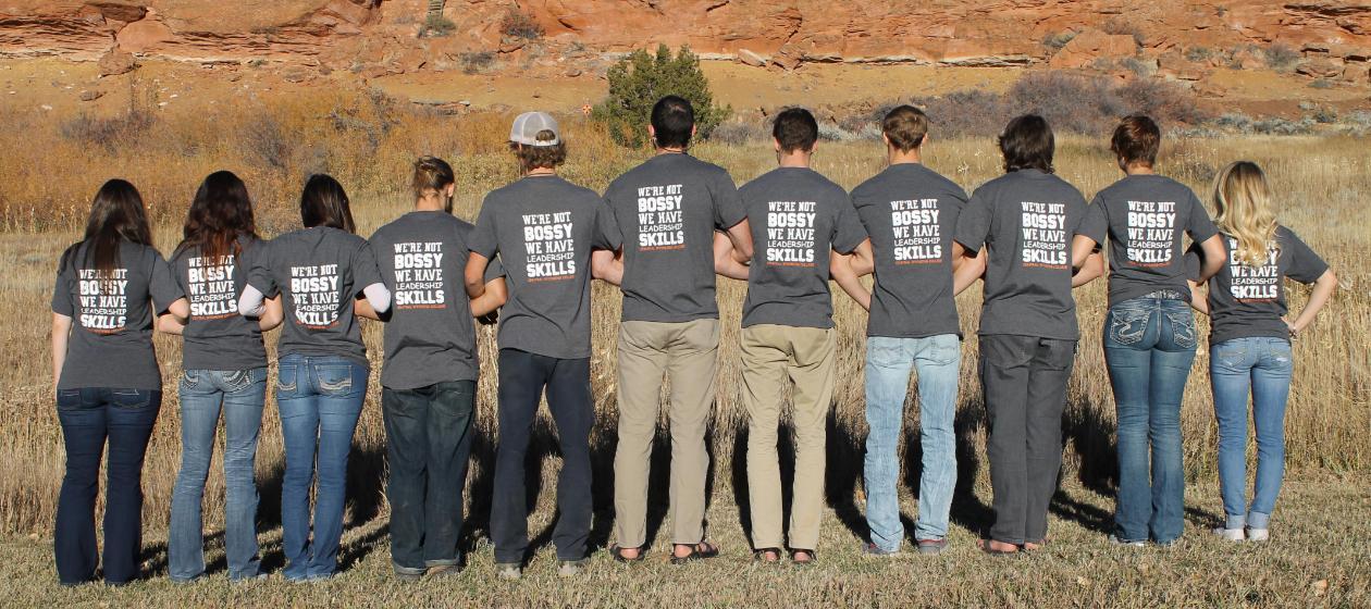 A line of students standing facing away from camera wearing leadership shirts